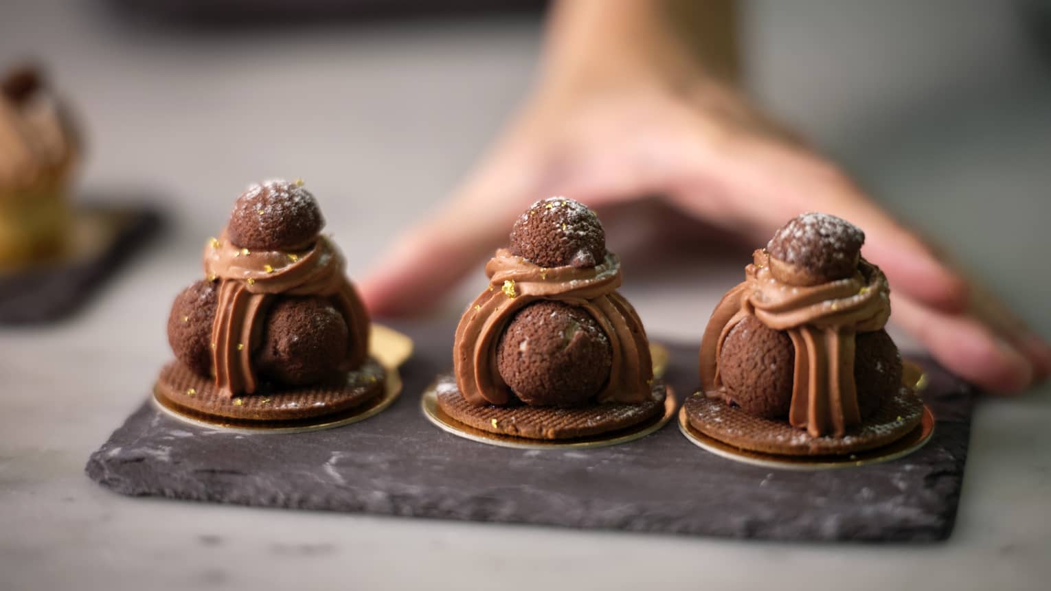 Three chocolate truffles on a piece of granite.