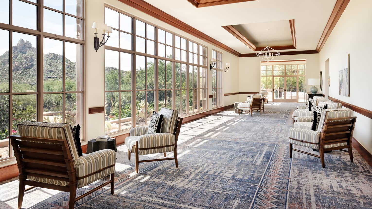 A foyer with large cloth chairs and large windows covering the walls.