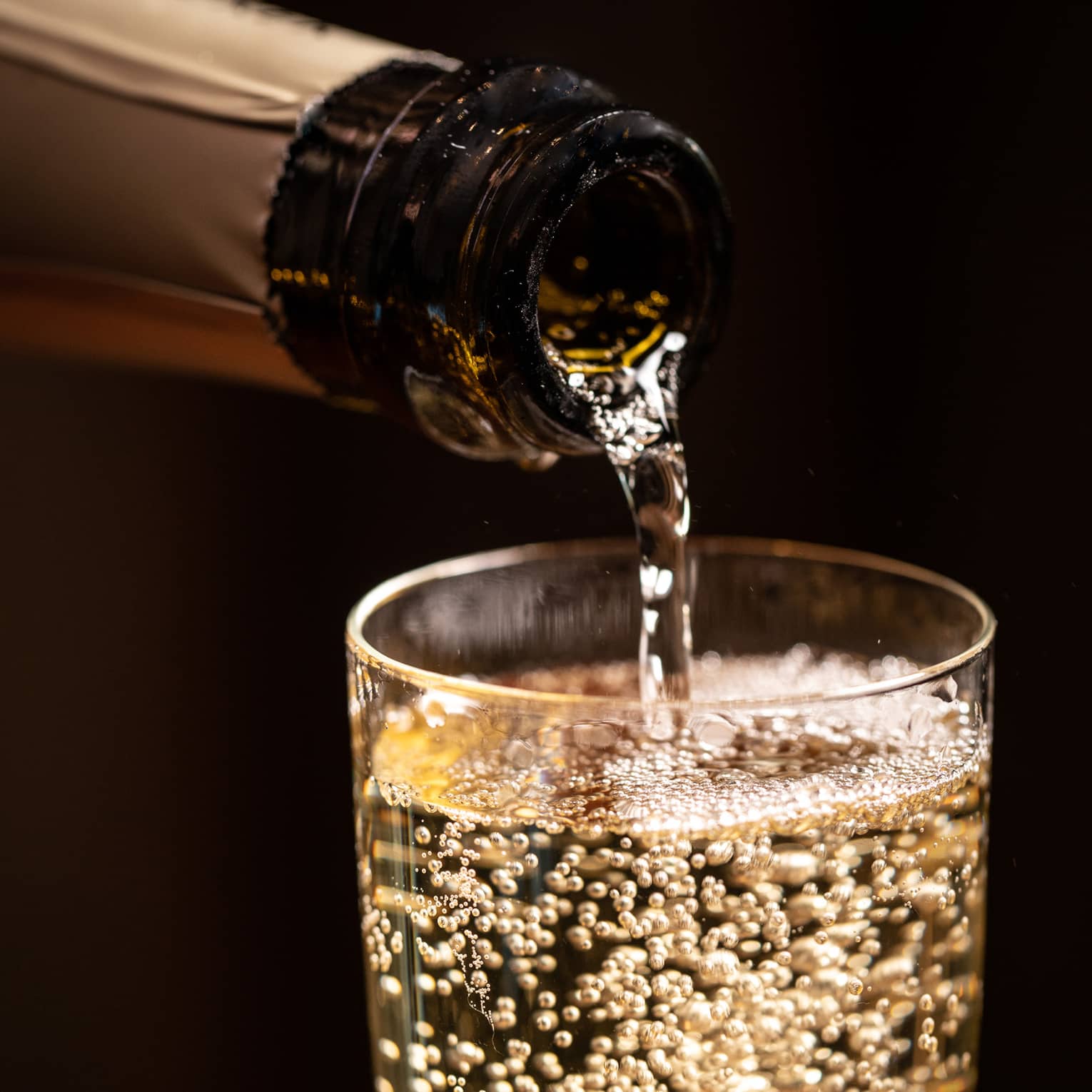 A bottle of wine being poured into a glass.
