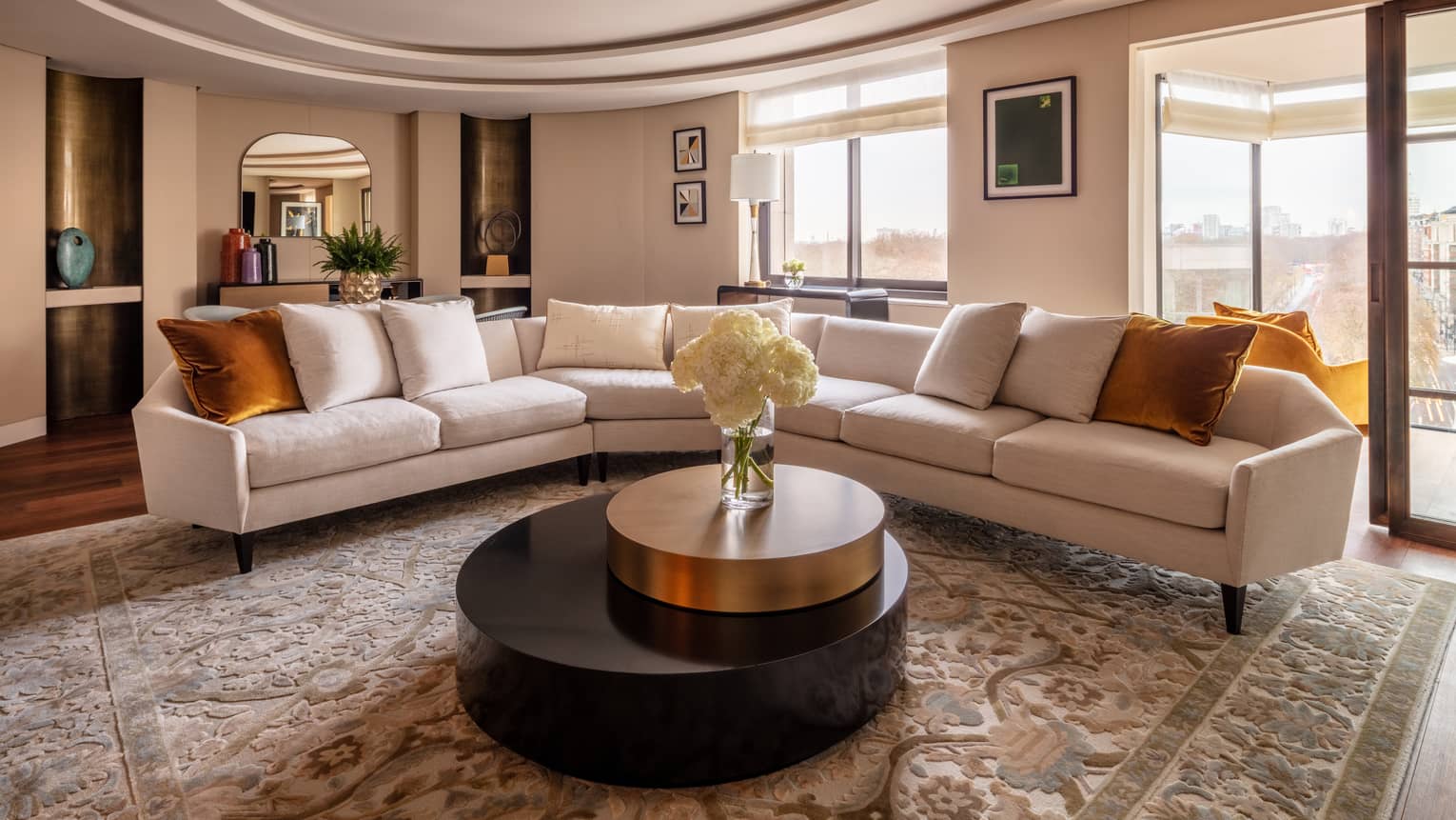 Hyde Park Suite living room with beige sectional, round coffee table with white flowers in vase