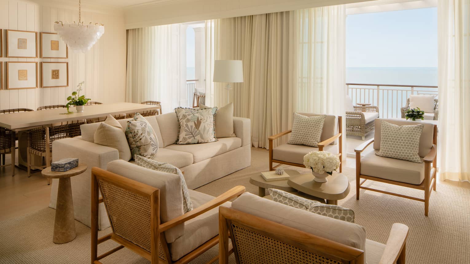 Luxury resort suite featuring a light-filled living room with off-white seating and a dining area
