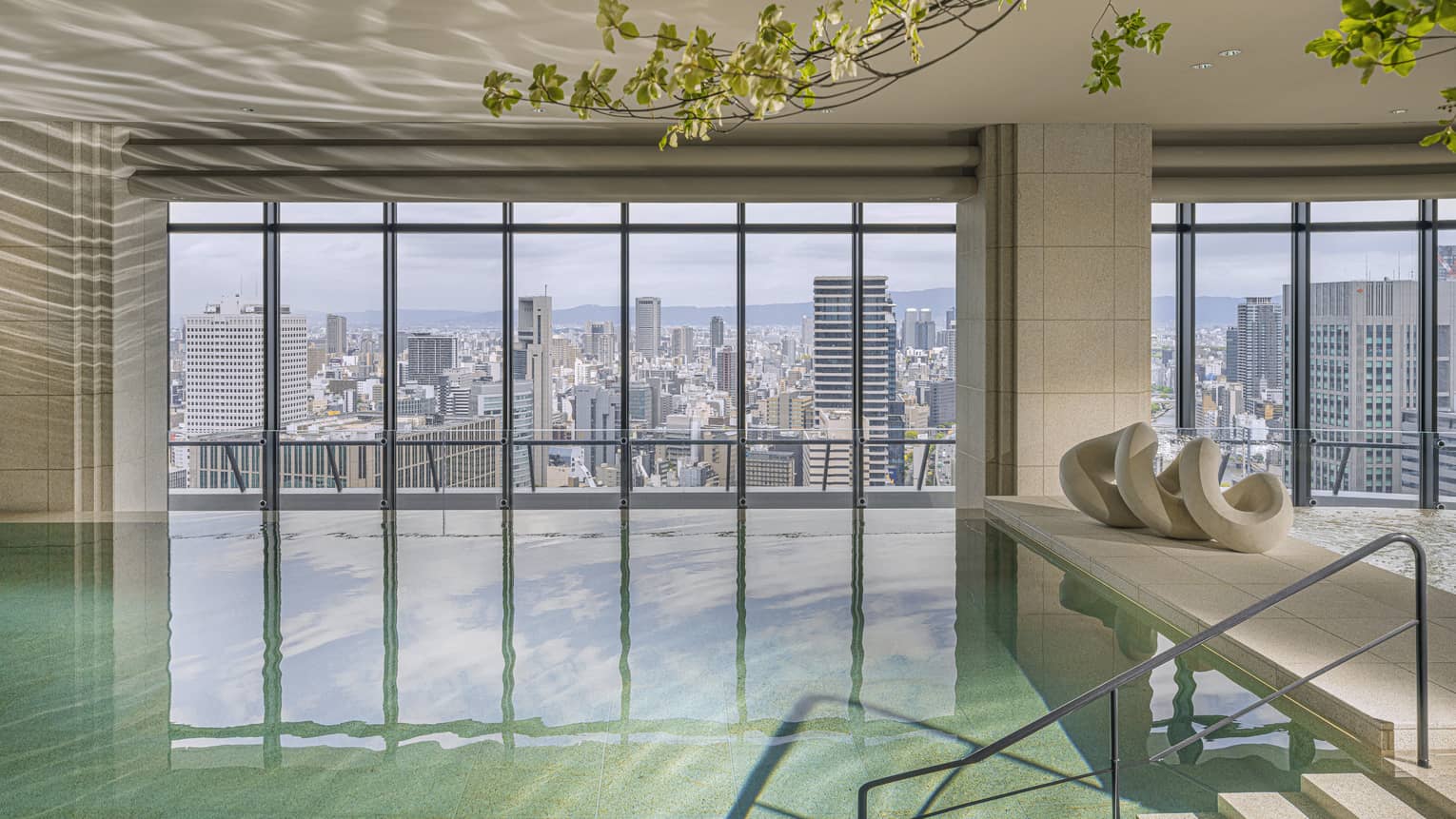 Indoor pool at Four Seasons Hotel Osaka, with wall of windows looking out to Osaka city