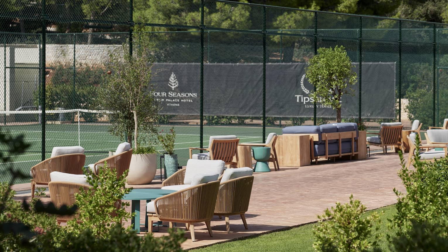 A tennis court with seating outside a fence.