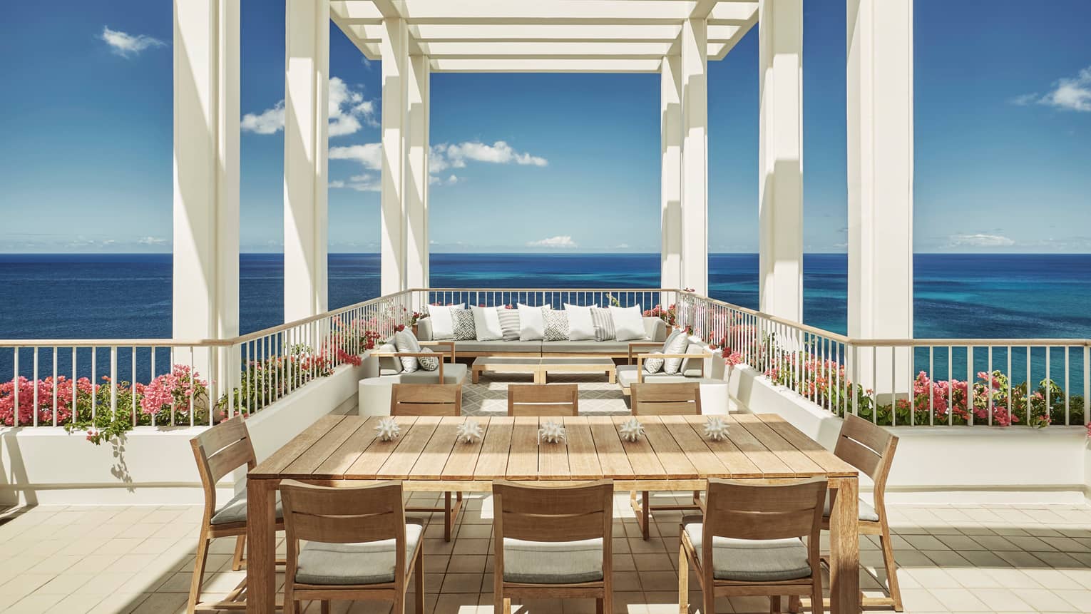 Penthouse Suite large patio dining table, seating area under white pergola, blue sky