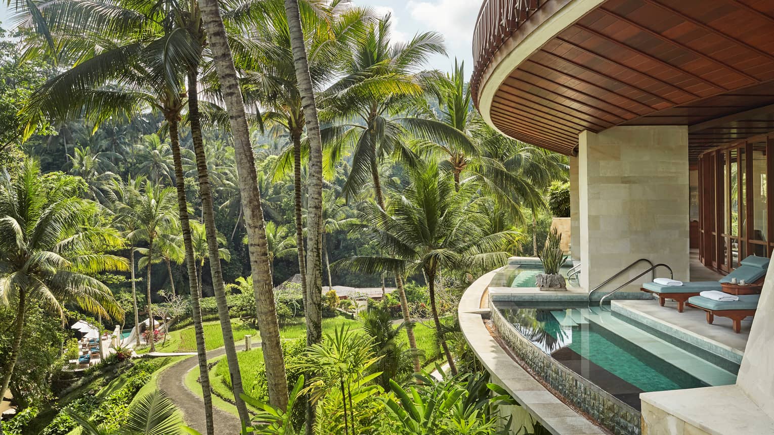 Curved private balcony with plunge pool at edge of terrace, blue lounge chairs, sunny garden far below