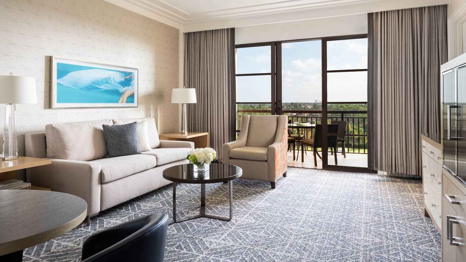 Living room with beige sofa, tan armchair, coffee table, walk-out balcony, grey carpet