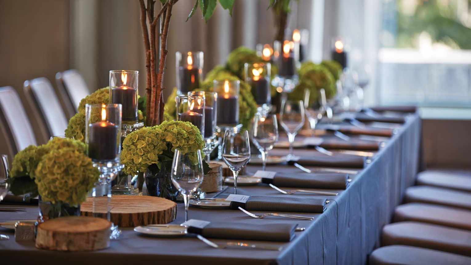Black pillar candles in votives, green flowers, wine glasses along banquet table