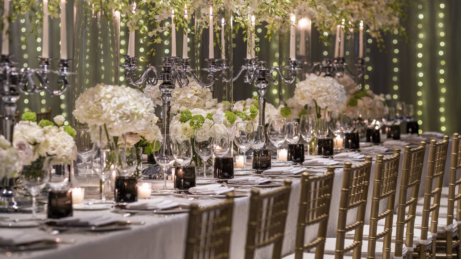 Elaborate white flowers and candelabras serve as the centerpiece of a dining arrangement