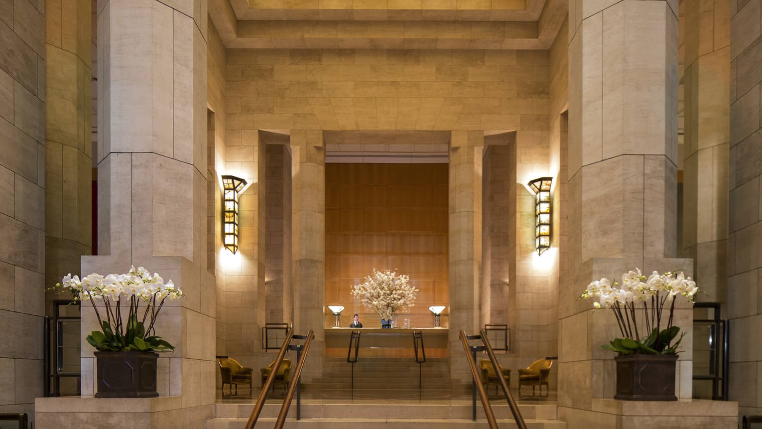 Tall marble columns, steps to hotel reception under amber skylight