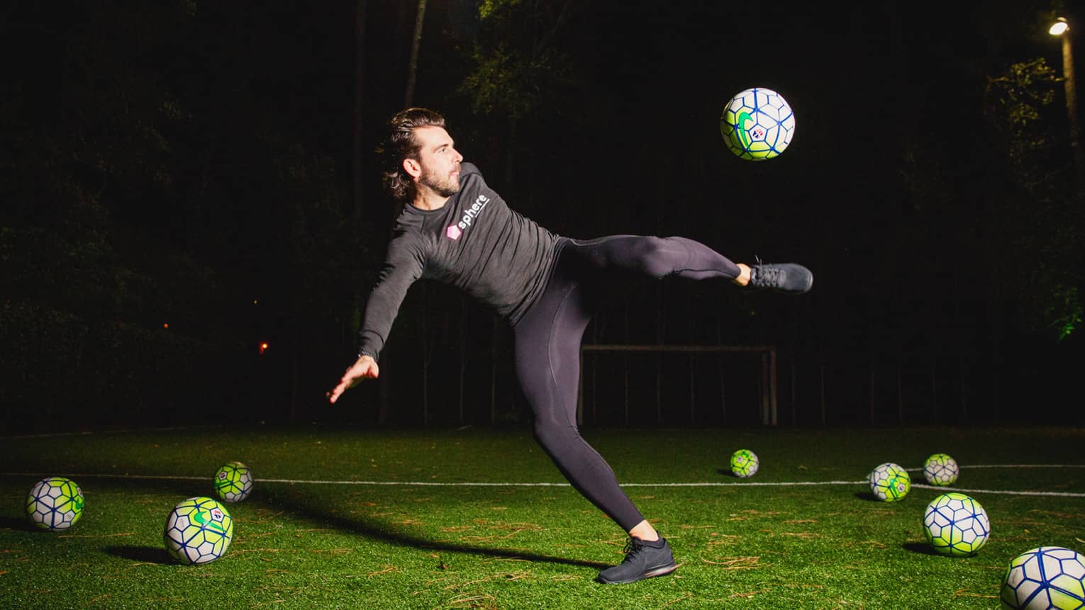 POWA by sphere session, Michael Chabala kicks soccer ball in mid-air on field with multiple balls at night