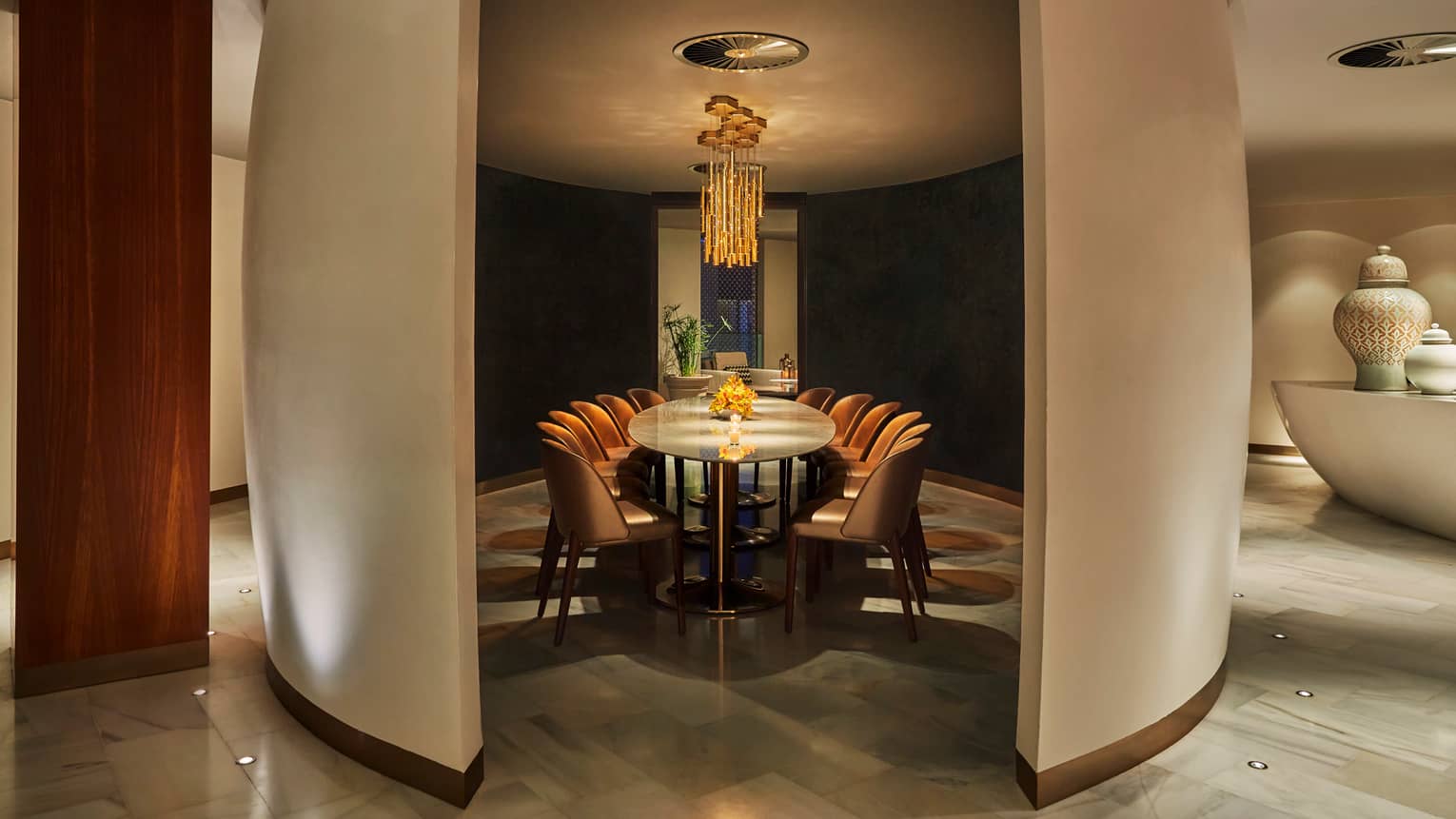 Modern private dining table for 12 within curved dividers, under modern orange chandelier 