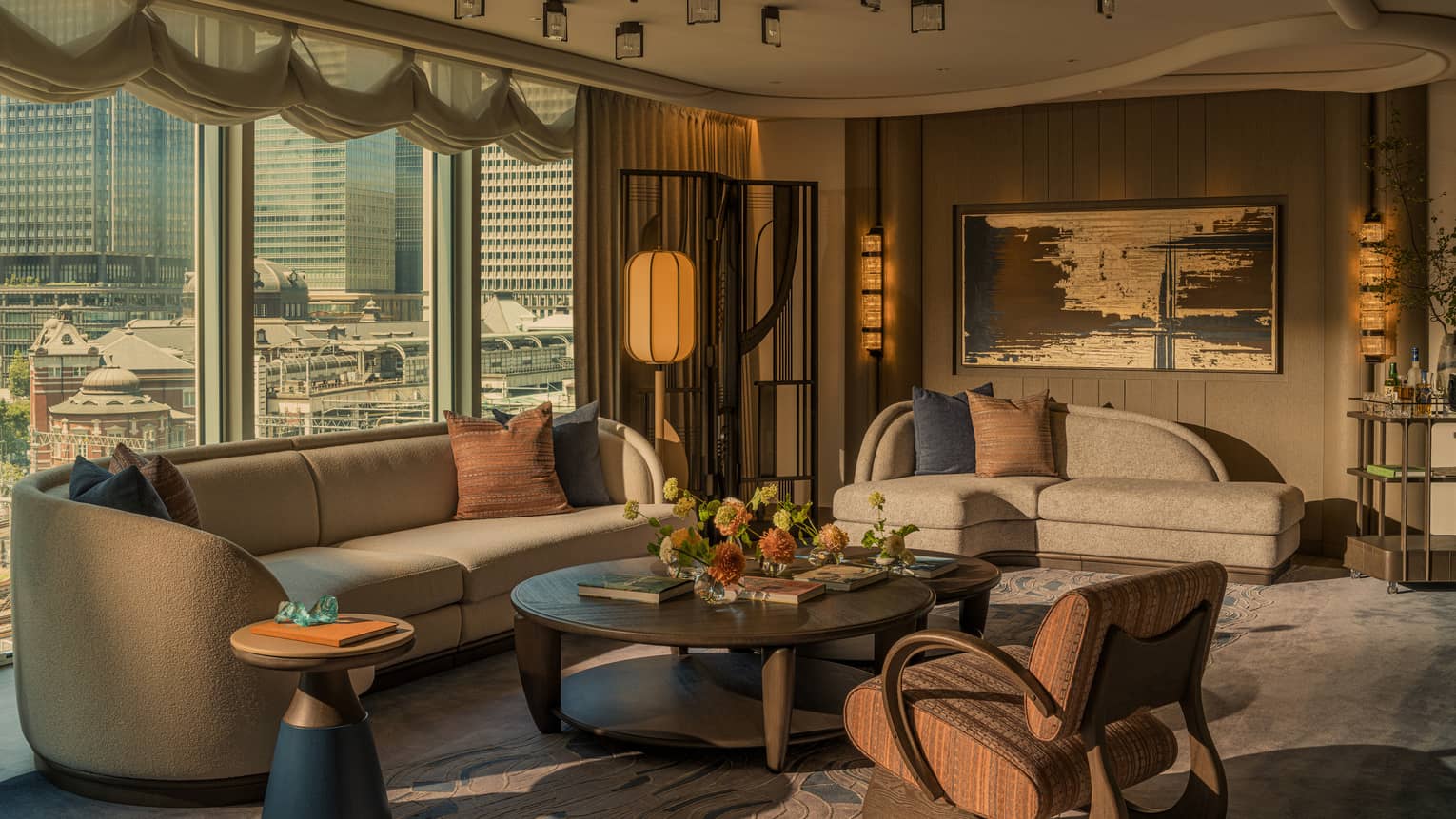 Luxury hotel suite living room with city views, two sofas, large coffee table and arm chair