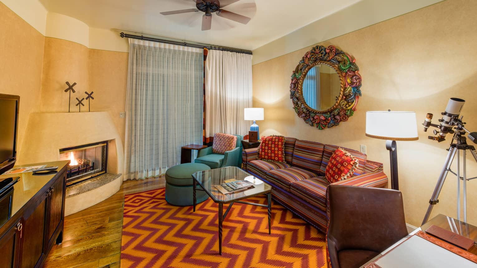 Oasis One-Bedroom Suite colourful striped sofa, armchair, mirror frame in front of gas fireplace