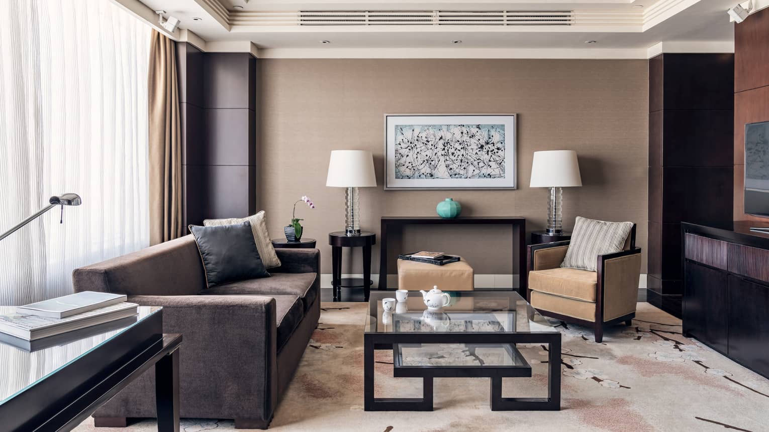 Brown coach, tan accent chair, glass nesting coffee table, brown and tan decor, floor-to-ceiling windows