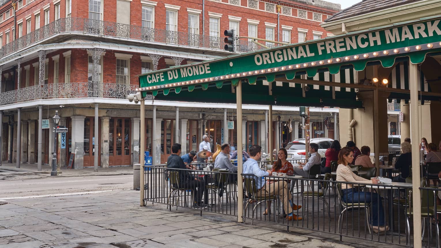 Many people eating outside of a large old building.