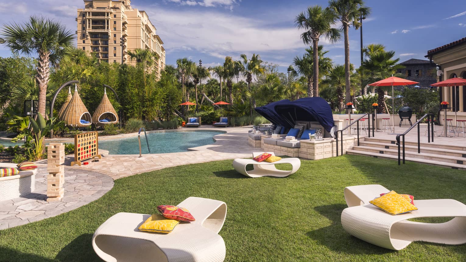 White patio chairs, hanging baskets, palm trees around swimming pool deck