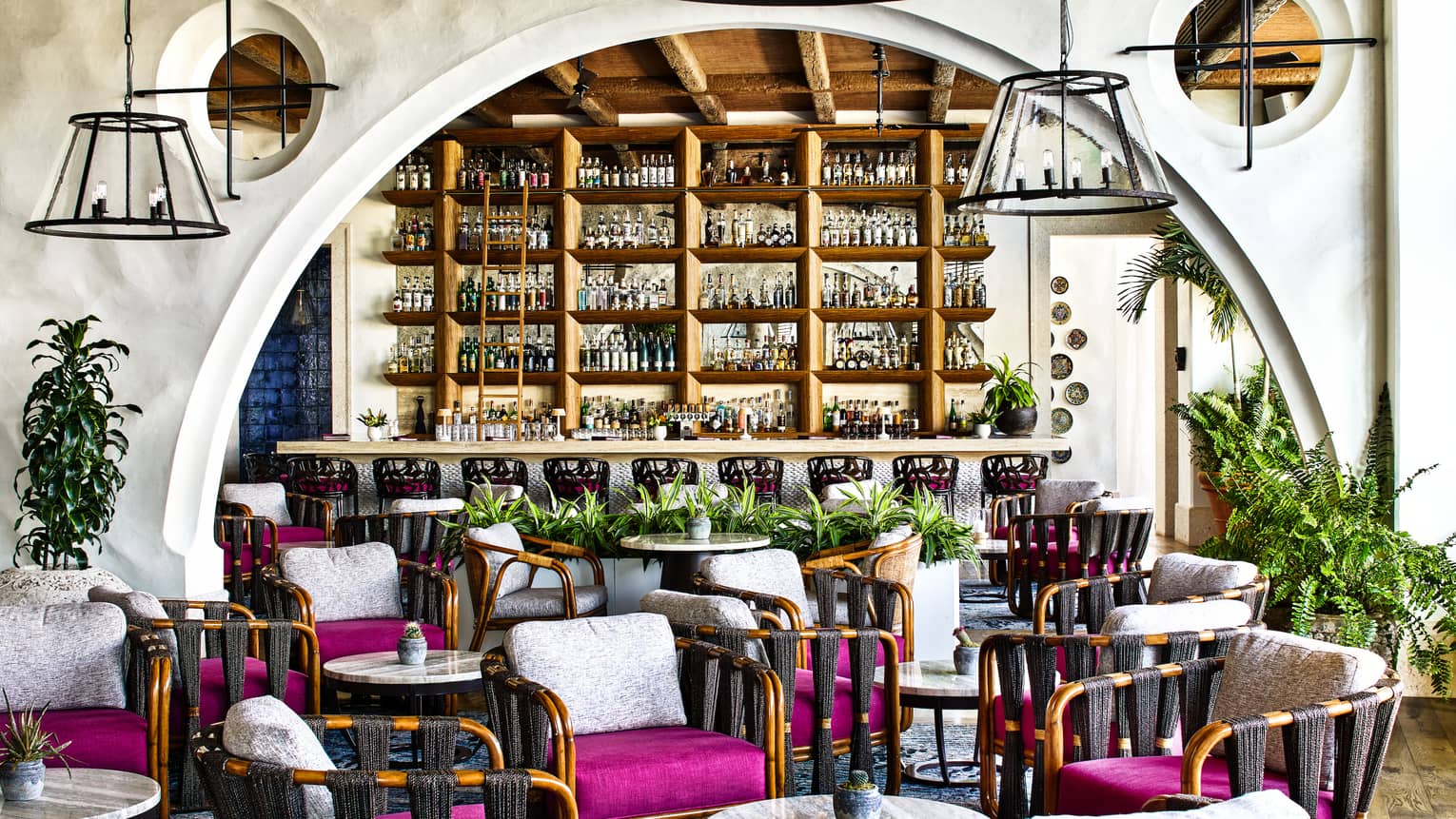 Restaurant with curved archway, various arm chairs with magenta seat cushions and white back cushions