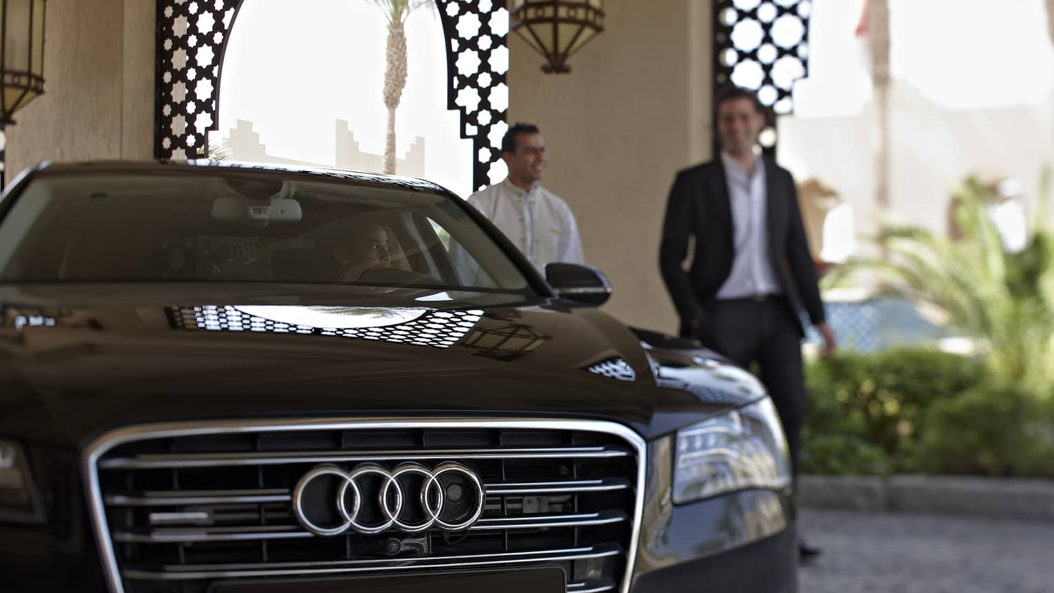 Black Audi car with two men standing beside it in the background