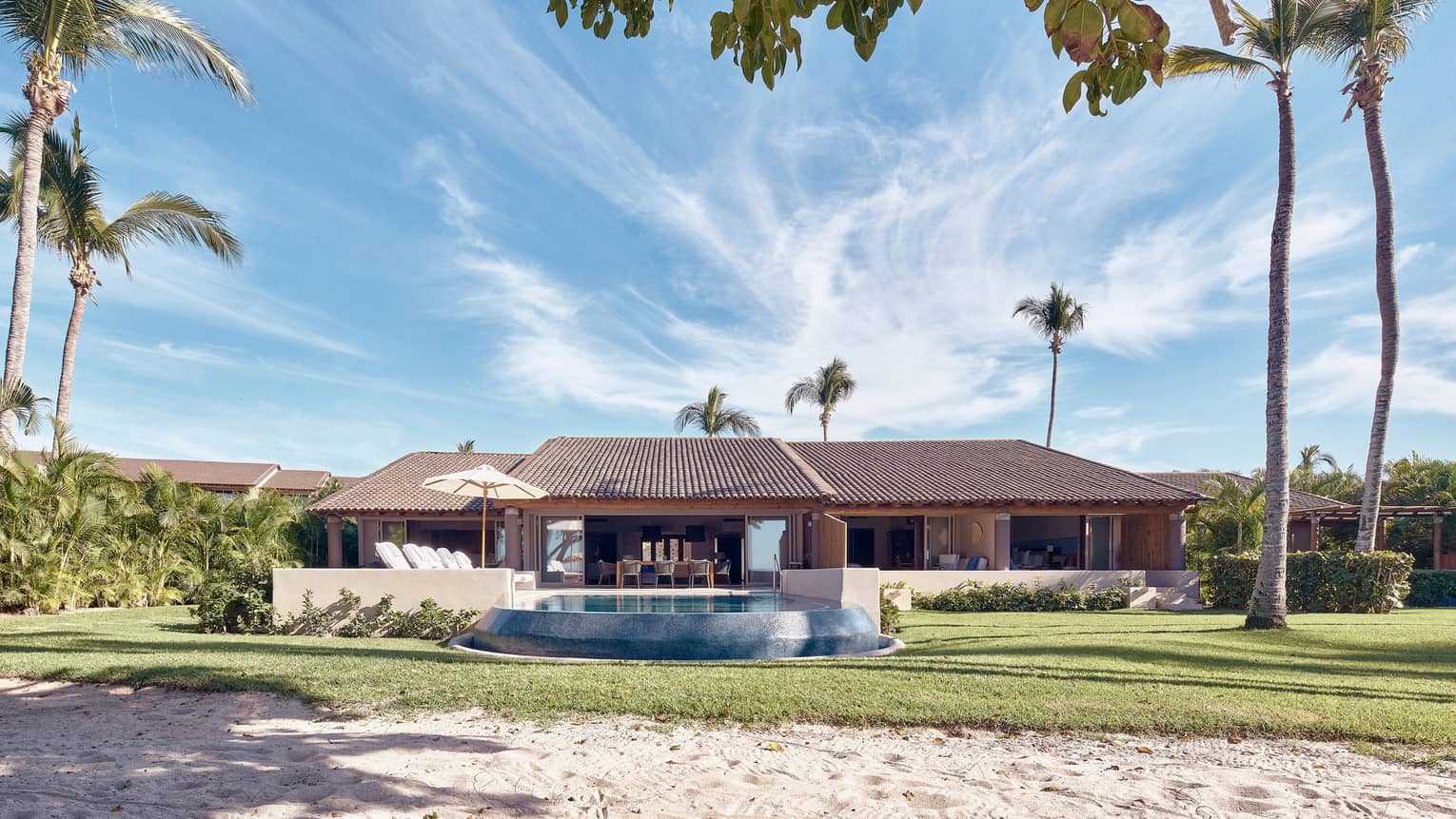 Arena Beach House exterior with palm trees and pool