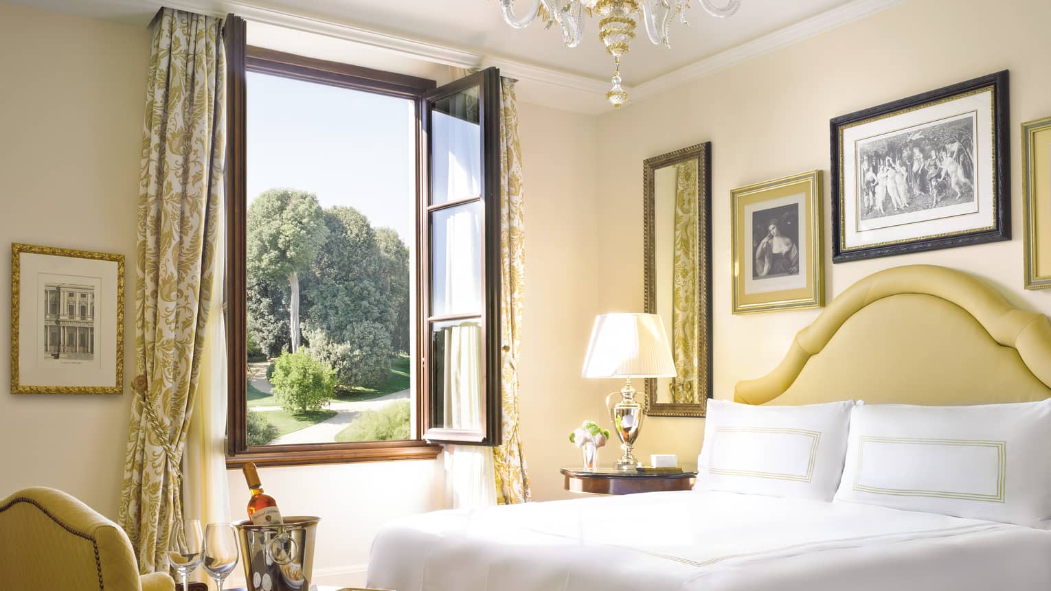 Premier Room bed with gold padded headboard, armchair, drapes by open window with wood frame