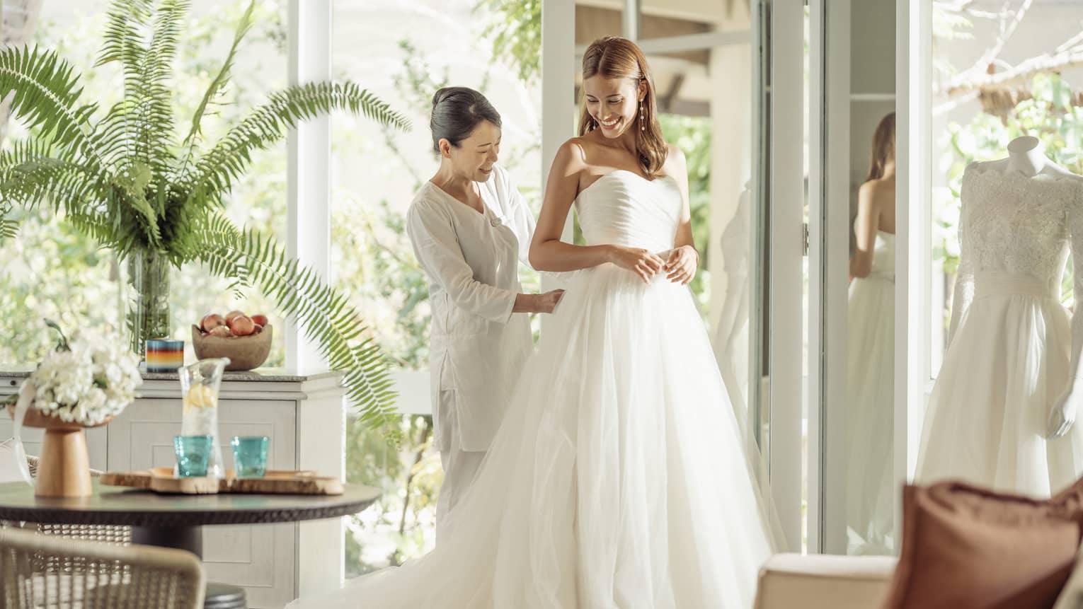 Wedding tailor helps bride in her wedding dress