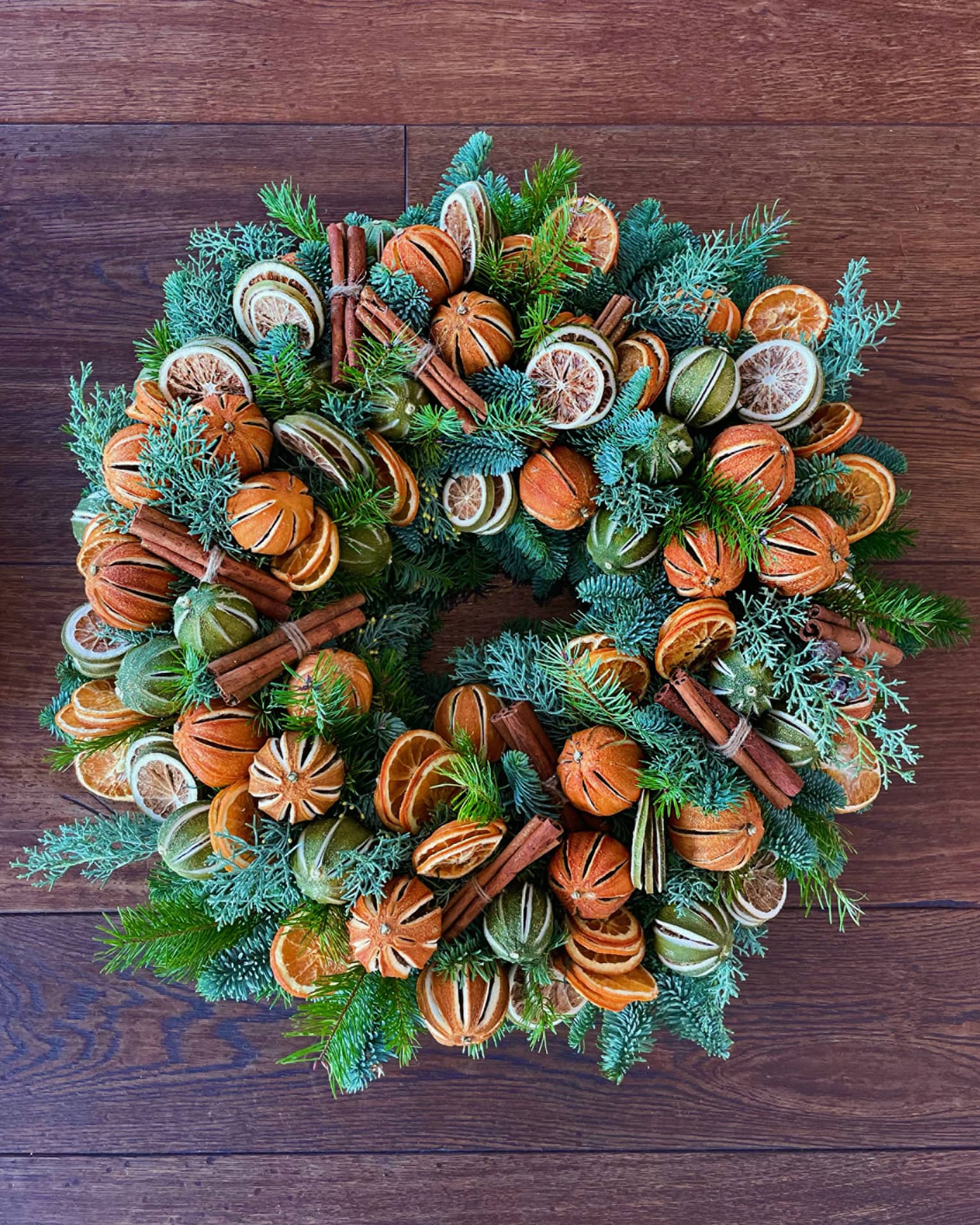 A wreath with greens and oranges.