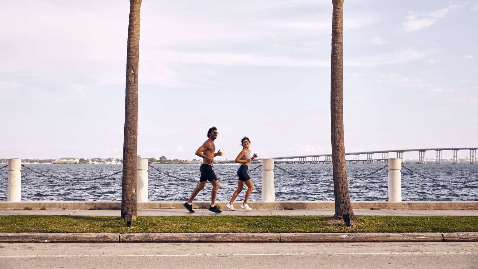 Man and woman running on sidewalk next to water