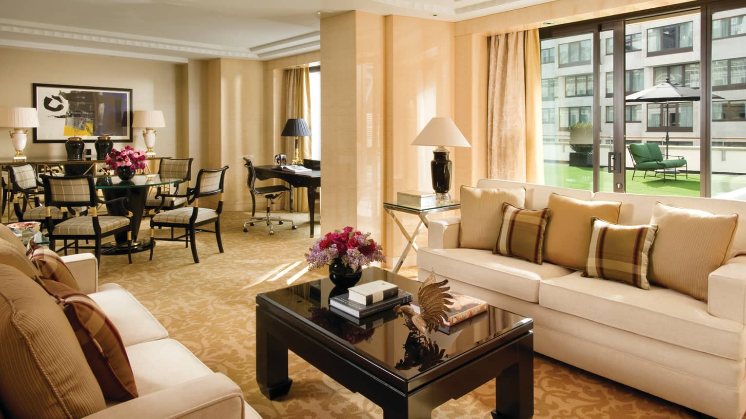 Terrace Suite living room, books, flowers on coffee table, dining room, large windows, patio