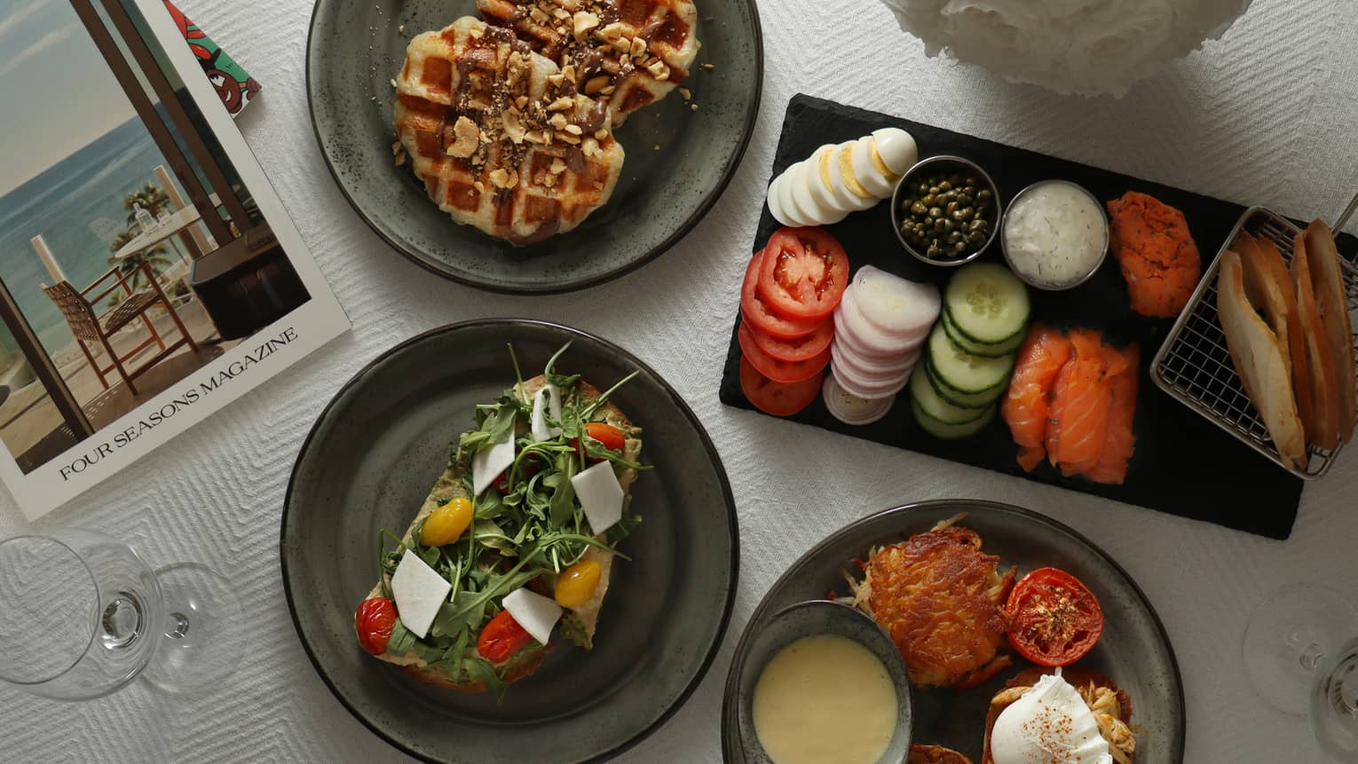An assortment of food, including vegetables, salad and waffles on black plates.