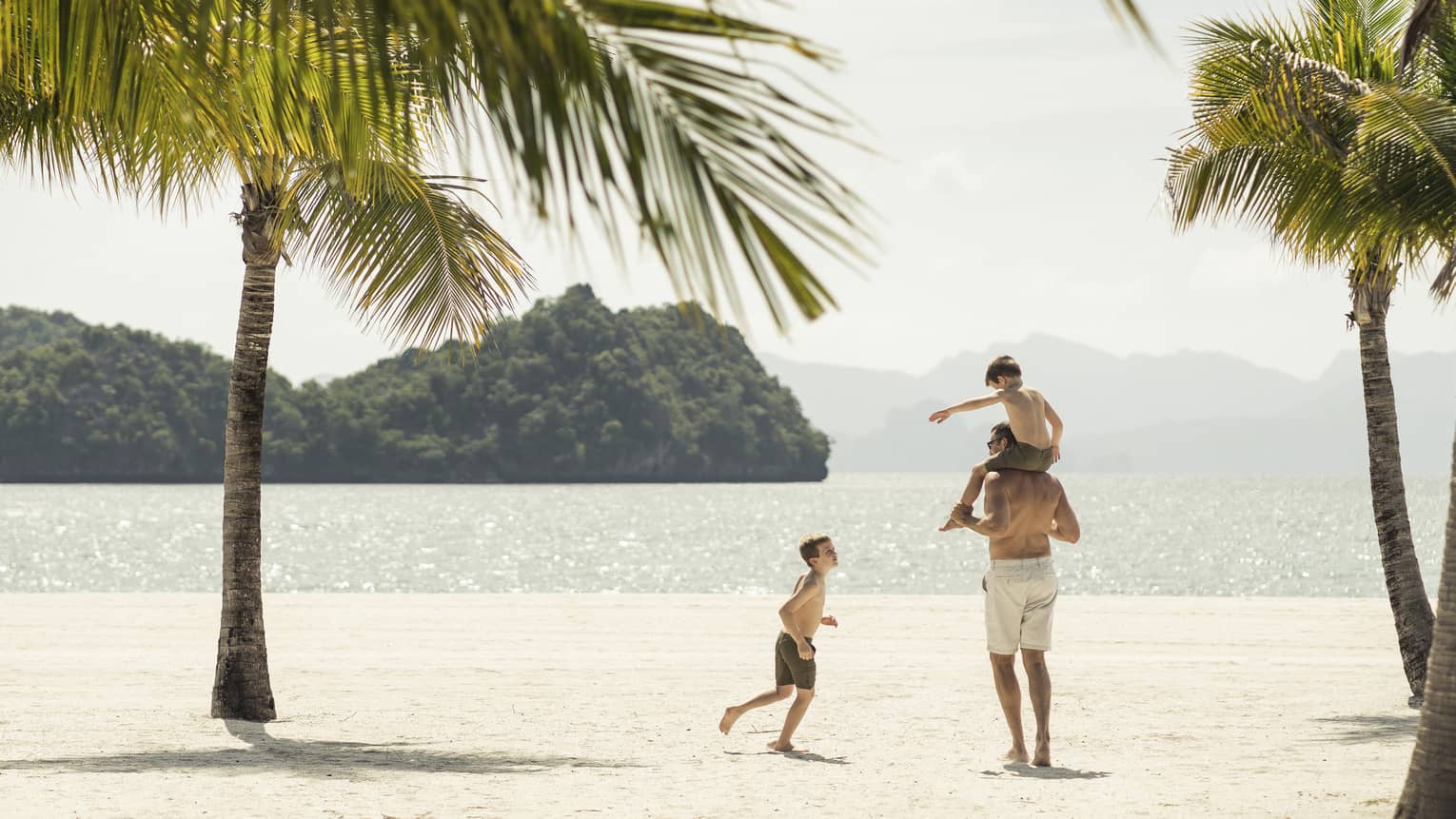 A man playing with two kids on the beach