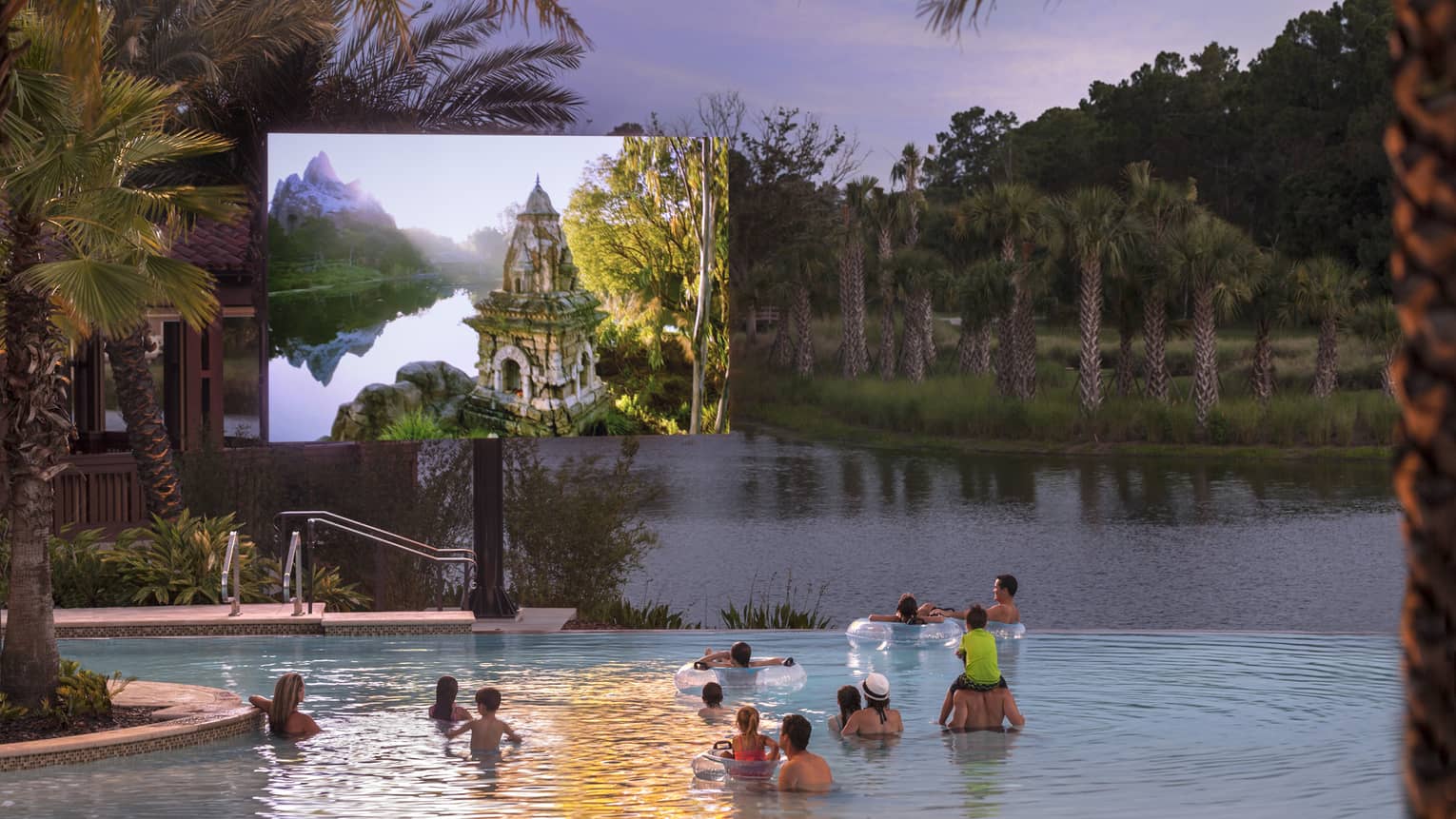 Under a dusk grey sky, adults and children watch a large outdoor screen while wading in a pool bordered by palm trees.