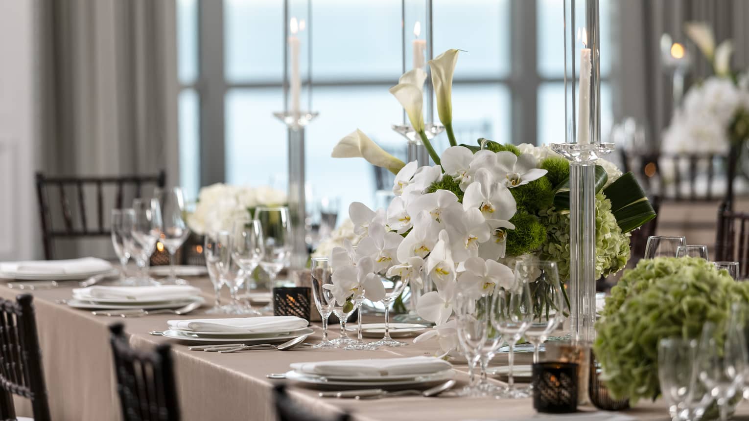 Part of formally set dining table with white orchids and tall crystal candlesticks