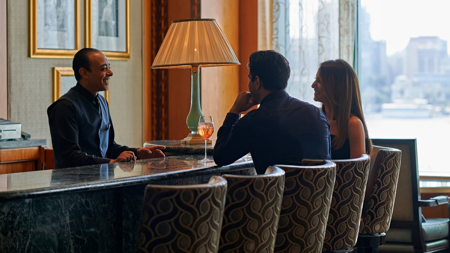 A couple enjoying cocktails at a bar with a city view