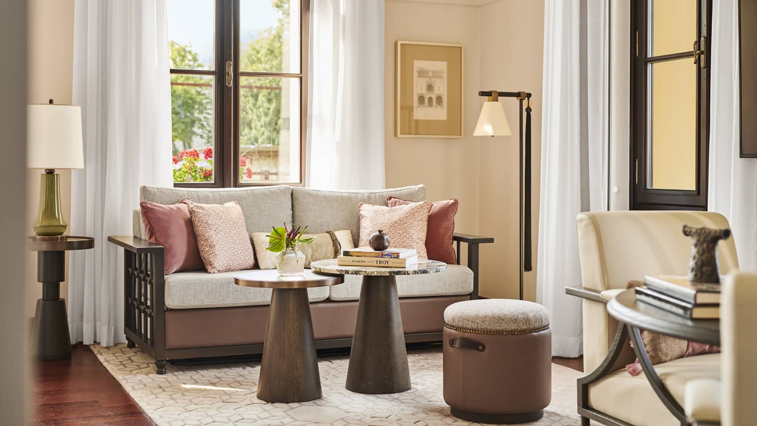 A hotel guest room with a small sofa, coffee table and large window.