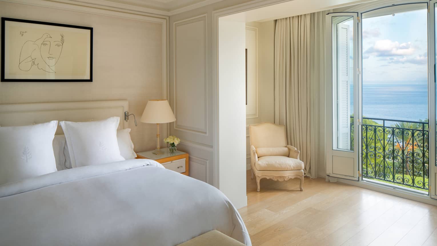 Palace Seaview Suite with white bed, framed line art above, white lamp and chaise, sea views