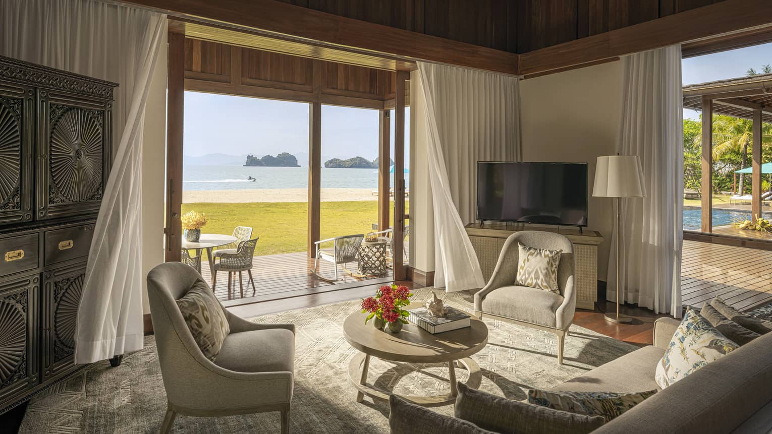 Sitting room with sofa and two chairs, with walk-out wooden terrace and beach view