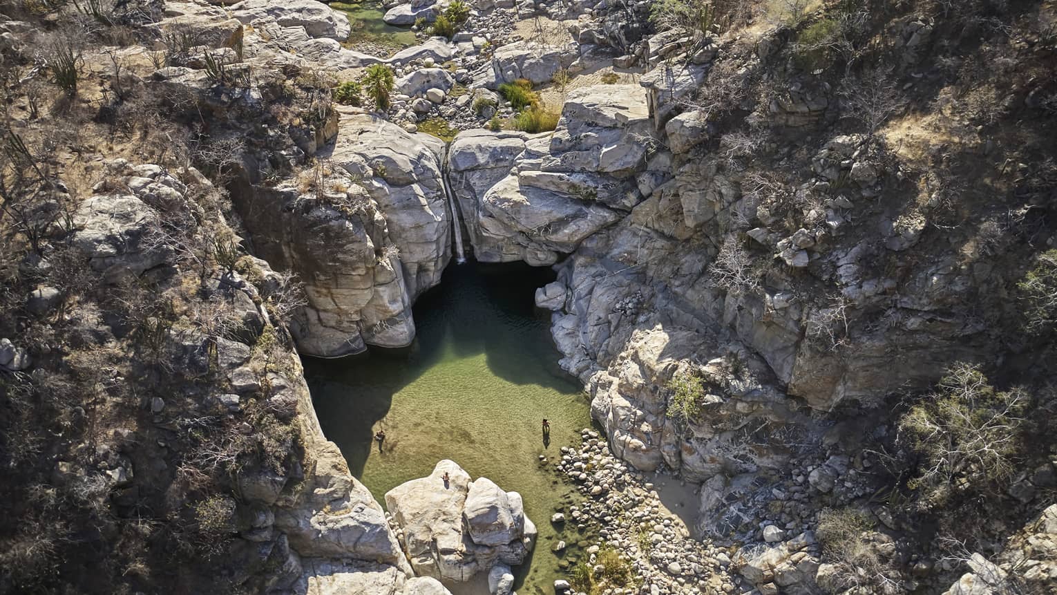 A waterfall and small pond surrounded by rocky cliffs.