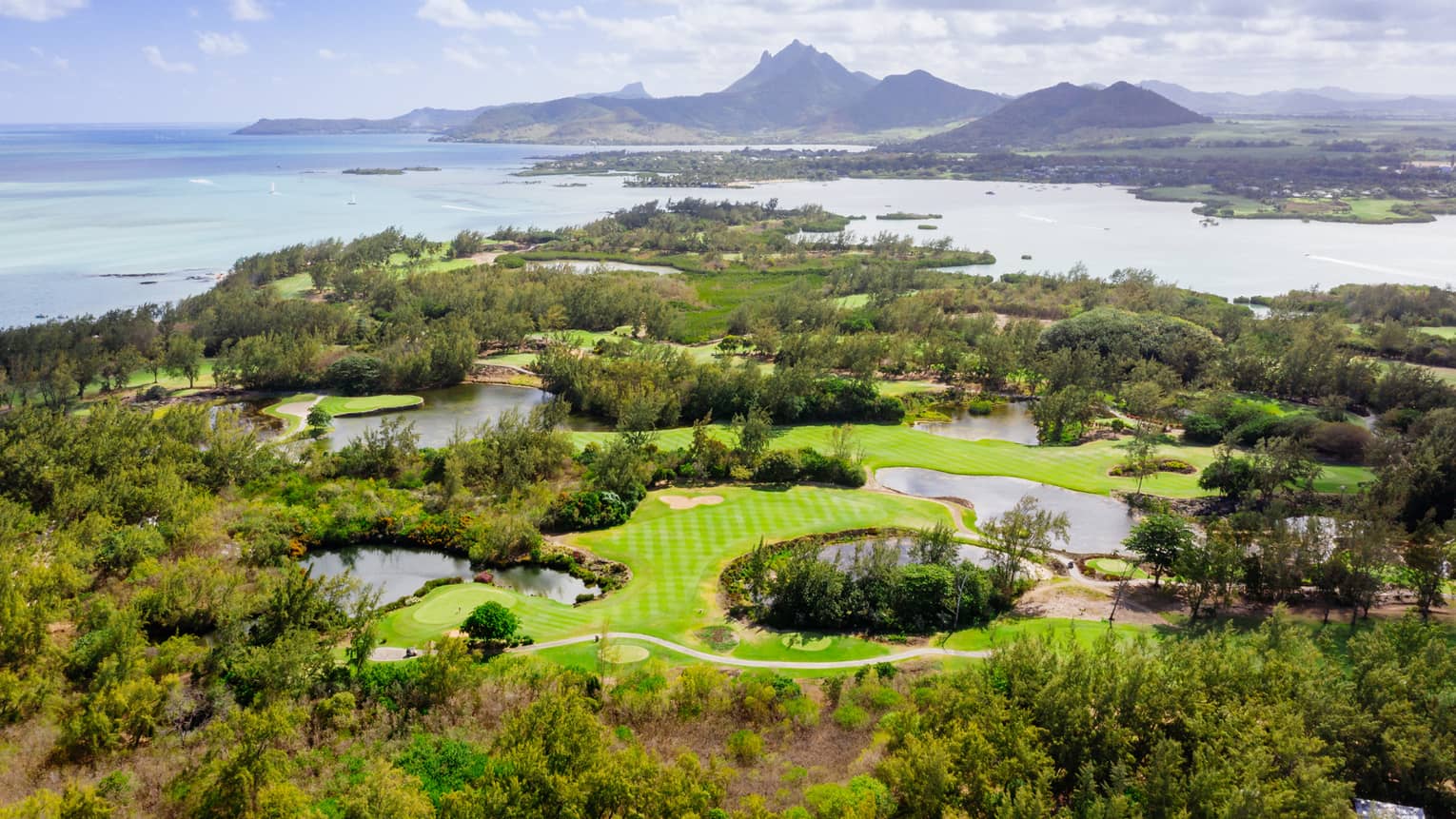 Aerial view of golf course with Indian Ocean and mountains in backdrop