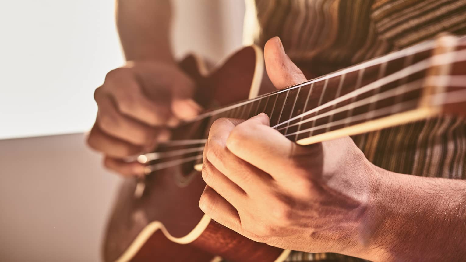 Close-up of hands playing ukulele stringed instrument