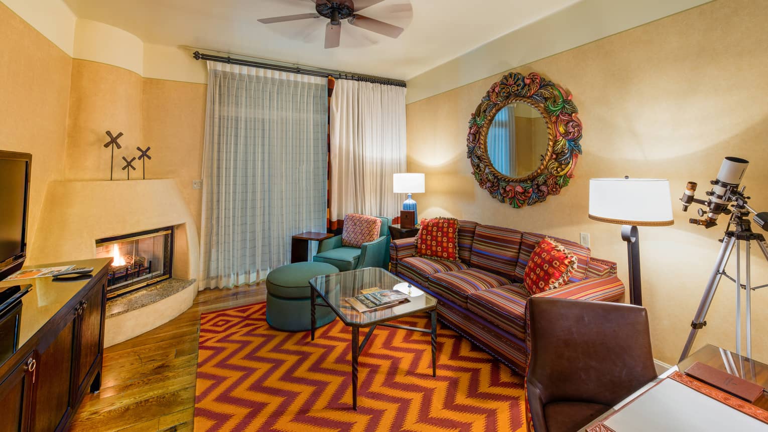 Oasis One-Bedroom Suite colourful striped sofa, armchair, mirror frame in front of gas fireplace