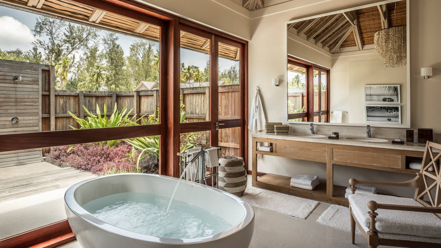 Water filling round soaking tub under window in bright bathroom