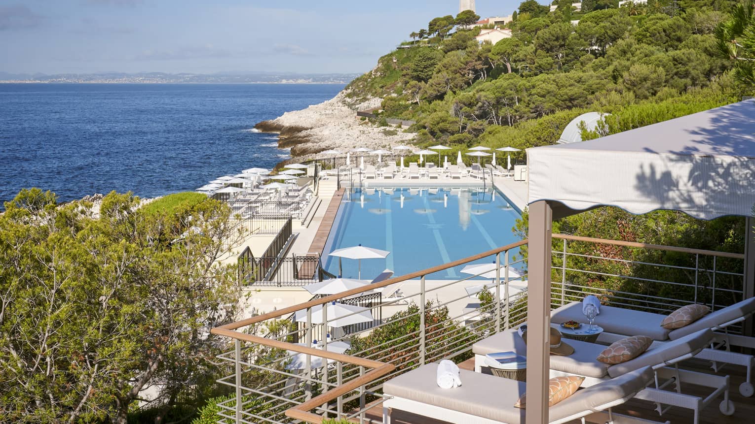 View from terrace of Club Dauphin pool, Mediterranean, green hillside and lighthouse