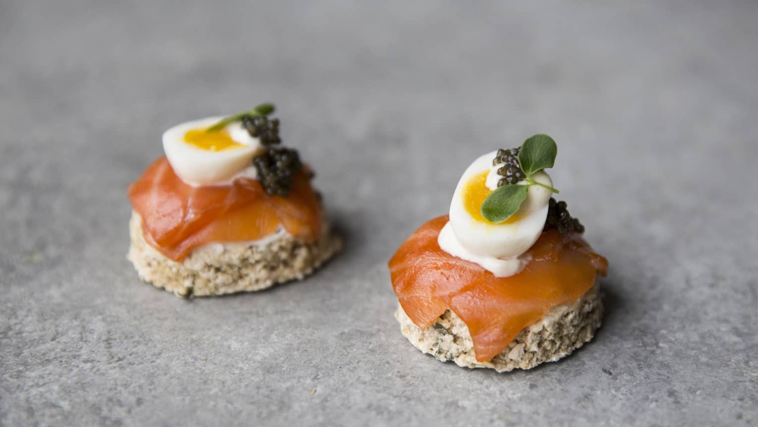 Toast rounds with smoked salmon, soft-cooked quail egg, caviar, microgreens garnish 
