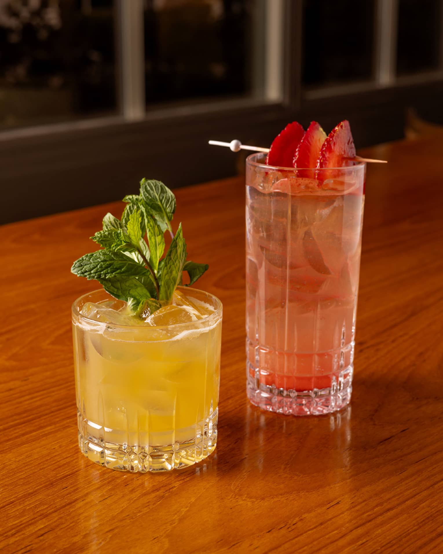 One yellow drink and one red drink placed beside each other on a dining table