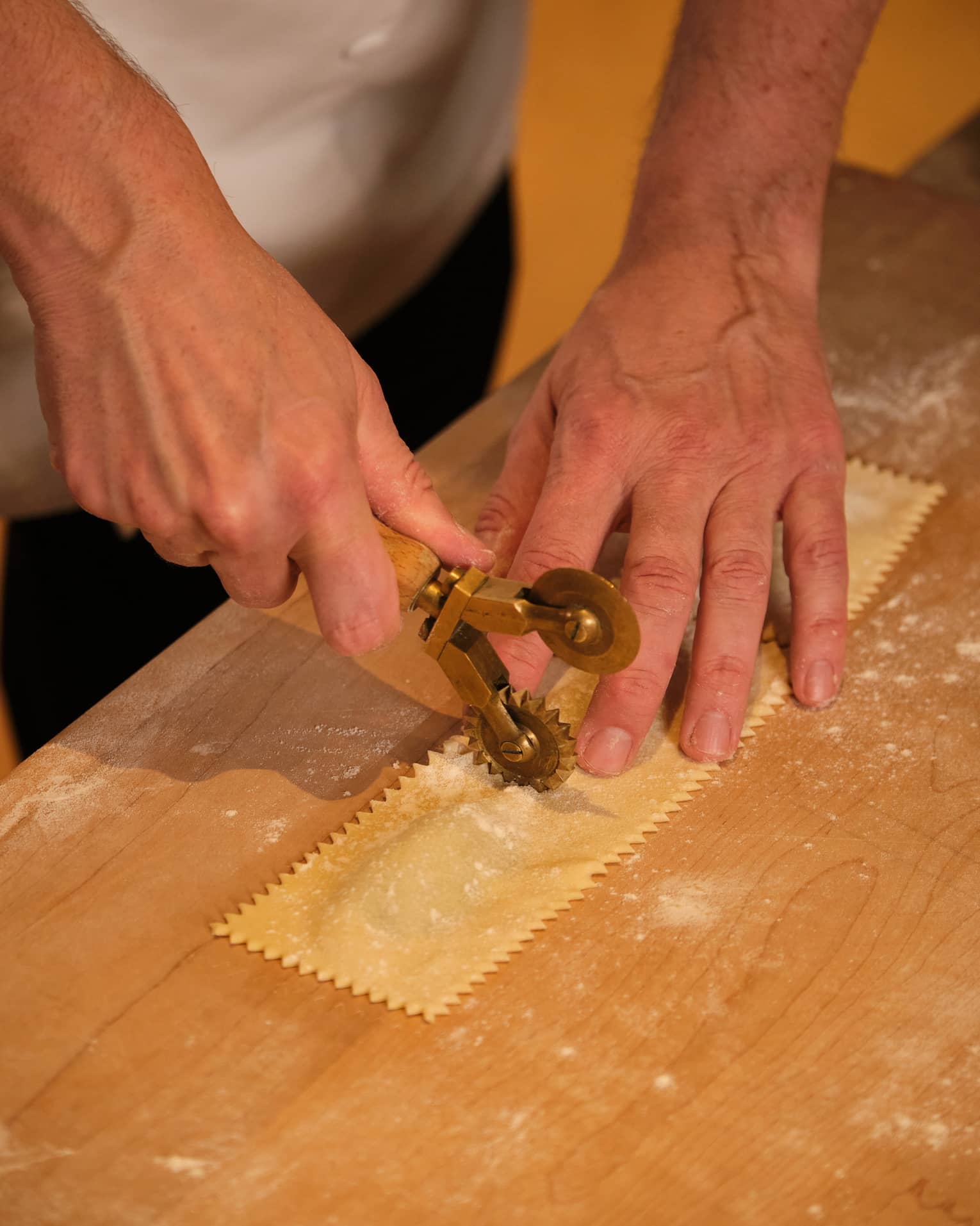 A chef crimping a sheet of ravioli pasta