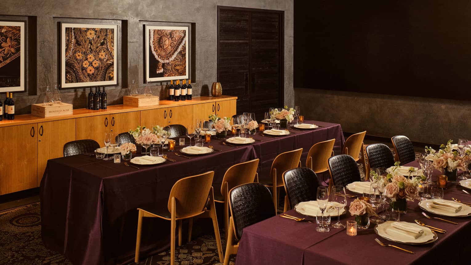 Private dining room with two table each set for 10 with burgundy tablecloths and floral arrangements in the centre