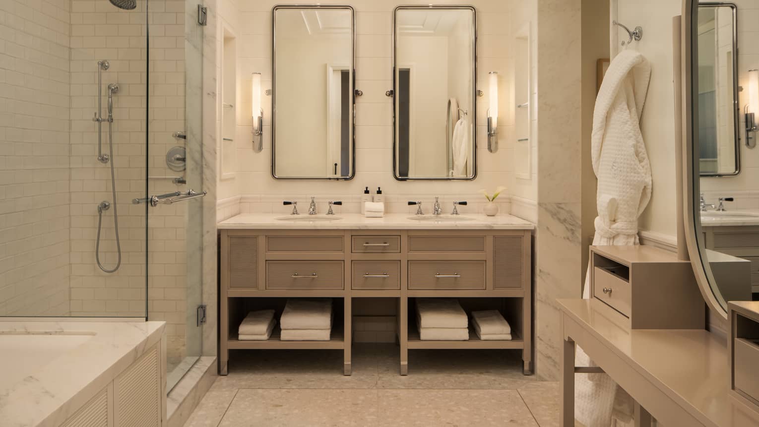 Luxury hotel bathroom with double vanity, glass-enclosed shower and bath tub