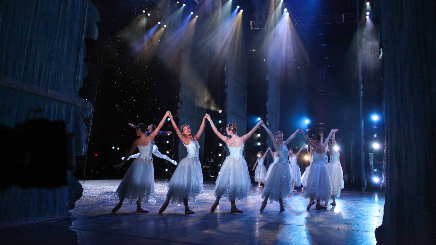 Ballet dancers wearing silvery blue costumes dance on a stage