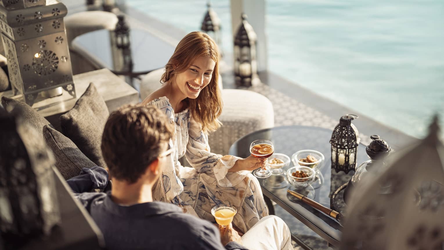 Smiling couple enjoys cocktails on the outdoor terrace of Al Barakat