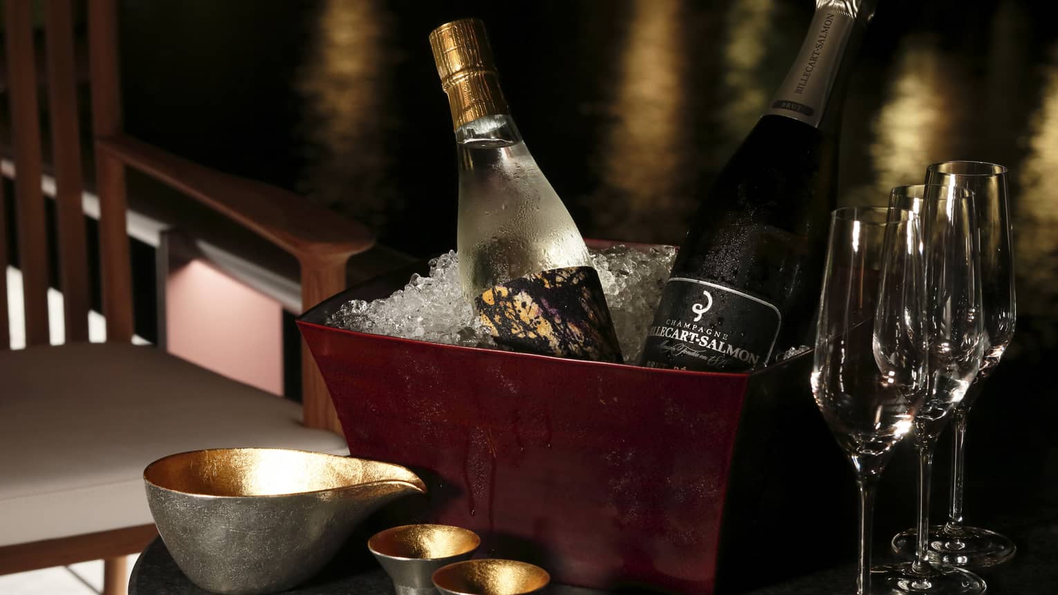 Bottles of sake and Champagne in brown ice bucket on table with glasses